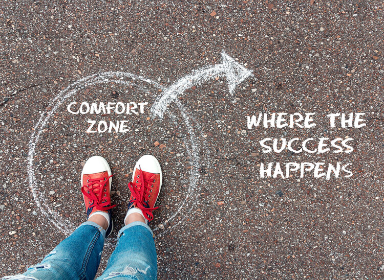 Exit from the comfort zone concept. Feet in red sneakers standing inside circle comfort zone and outward arrow chalky on the asphalt. Uncertainty Is the Only Thing That's Really Certain
