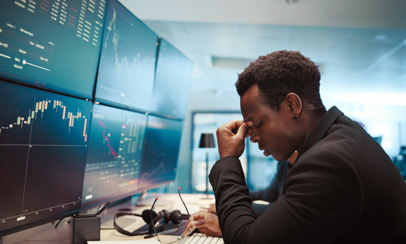 Trading, man and broker with headache by computer for stock market crash, financial crisis and bad investment. Screen, black person or stress for finance loss, exchange risk or price plummet at night.